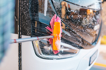 Young male worker washing bus.