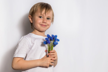 Portrait of the beautiful child holds a bouquet of blue flowers for her mother.