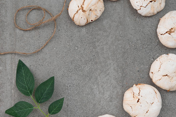 Chocolate meringues lie in a semicircle on a concrete background with a green twig with an empty place for text.