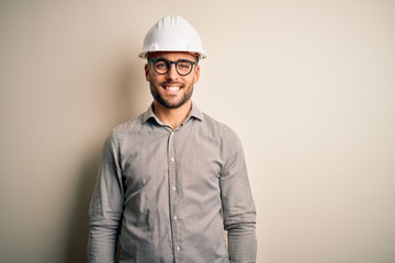 Young architect man wearing builder safety helmet over isolated background with a happy and cool smile on face. Lucky person.