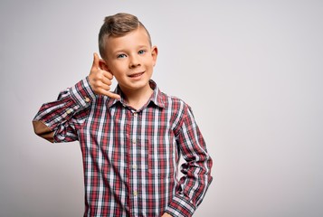 Young little caucasian kid with blue eyes wearing elegant shirt standing over isolated background smiling doing phone gesture with hand and fingers like talking on the telephone. Communicating