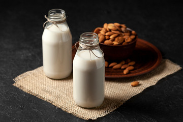 homemade almond milk in bottles with nuts on a black table, a variety of dairy products without sugar and lactose, a vegetarian drink