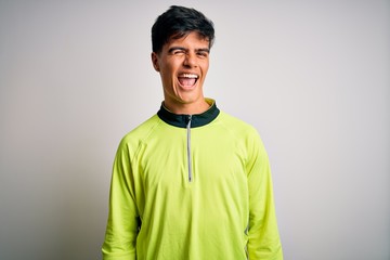 Young handsome sportsman doing sport wearing sportswear over isolated white background winking...