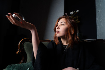 Woman in black suit holding crystal ball