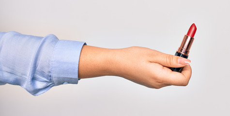 Hand of caucasian young woman holding red lipstick over isolated white background