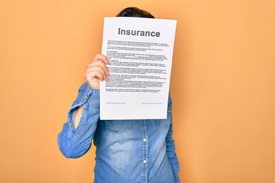 Woman holding insurance document paper standing over isolated yellow background