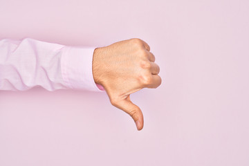 Hand of caucasian young man showing fingers over isolated pink background doing thumbs down...