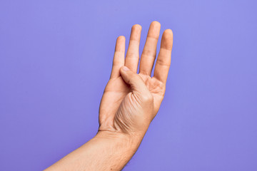Hand of caucasian young man showing fingers over isolated purple background counting number 4 showing four fingers