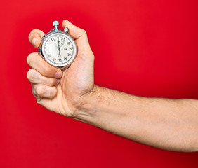 Beautiful hand of man holding stopwatch doing countdown over isolated red background