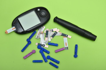 1 glucometer, lancet, spare needles on green background 