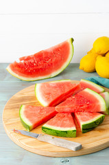 Slices of watermelon and lemons on a wood cutting board and wooden background