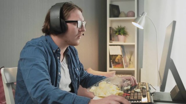 Side view of young man playing video game at home feeling Upset after losing and showing indecent gesture