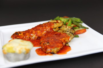 Grilled Chicken Topped with Red Moroccan Sauce served in a White Ceramic Dish