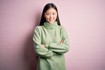 Young beautiful asian woman wearing green winter sweater over pink solated background happy face smiling with crossed arms looking at the camera. Positive person.