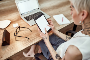 Checking e-mail. Back view of young stylish blonde tattooed business woman using her touchpad while...