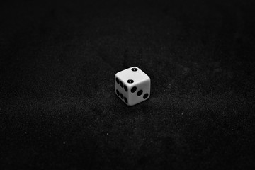 One white dice showing two on black background