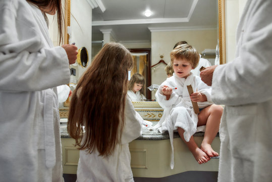 Getting Ready To Go Out. Cropped Shot Of Parents And Two Kids In White Bathrobes Having Beauty, Morning Routine In Hotel Bathroom, Standing Near The Mirror. Family, Travel, Resort, Vacation Concept