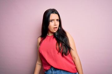 Obraz premium Young brunette woman wearing casual summer shirt over pink isolated background In shock face, looking skeptical and sarcastic, surprised with open mouth