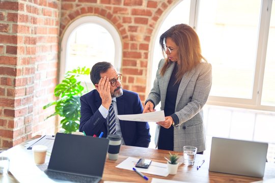 Two middle age business workers working together. Woman bullying man at the office