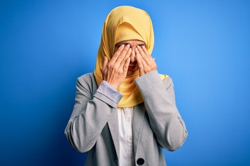 Middle age brunette business woman wearing muslim traditional hijab over blue background rubbing eyes for fatigue and headache, sleepy and tired expression. Vision problem