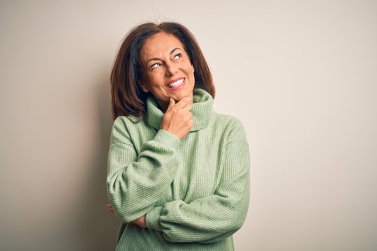 Middle age beautiful woman wearing casual turtleneck sweater over isolated white background with hand on chin thinking about question, pensive expression. Smiling with thoughtful face. Doubt concept.