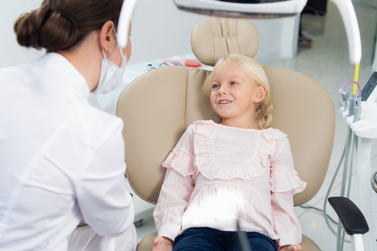 Image of little female child having teeth checked by doctor in a