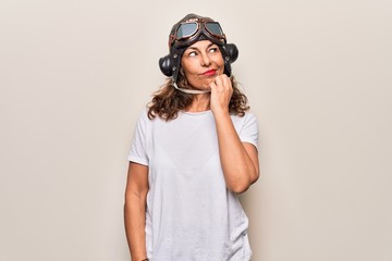 Middle age brunette woman wearing goggles and retro aviator leather hat over white background...