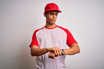 Young handsome african american sportsman wearing striped baseball t-shirt and cap Checking the time on wrist watch, relaxed and confident