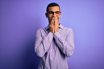 Fototapeta premium Handsome african american man wearing striped shirt and glasses over purple background laughing and embarrassed giggle covering mouth with hands, gossip and scandal concept