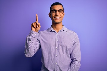 Handsome african american man wearing striped shirt and glasses over purple background showing and...