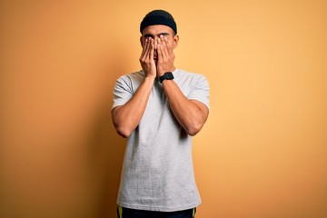 Handsome african american sportsman doing sport wearing sportswear over yellow background rubbing...