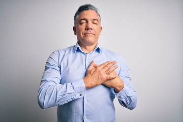 Middle age handsome grey-haired business man wearing elegant shirt over white background smiling with hands on chest with closed eyes and grateful gesture on face. Health concept.