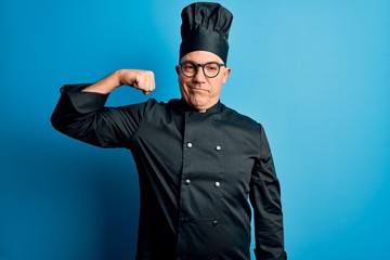 Middle age handsome grey-haired chef man wearing cooker uniform and hat Strong person showing arm muscle, confident and proud of power