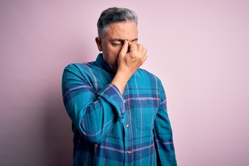 Fototapeta premium Middle age handsome grey-haired man wearing casual shirt over isolated pink background tired rubbing nose and eyes feeling fatigue and headache. Stress and frustration concept.