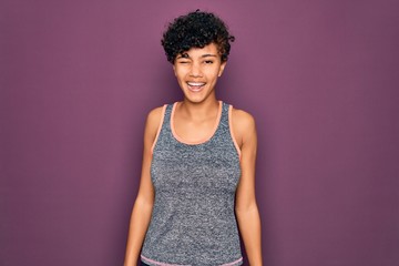 Young beautiful african american afro sportswoman doing exercise wearing sportswear winking looking...