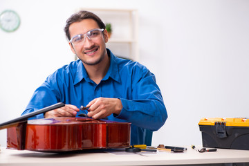 Young male repairman repairing cello