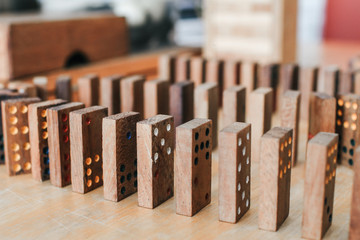 Playing dominoes on a wooden table. Dominoes game concept.Falling dominoes. Domino effect, chain...