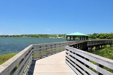 Obraz premium Wooden boardwalk during sunny summer with lake view