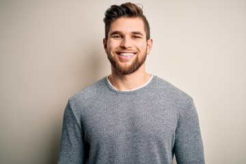 Young handsome blond man with beard and blue eyes wearing casual sweater with a happy and cool smile on face. Lucky person.