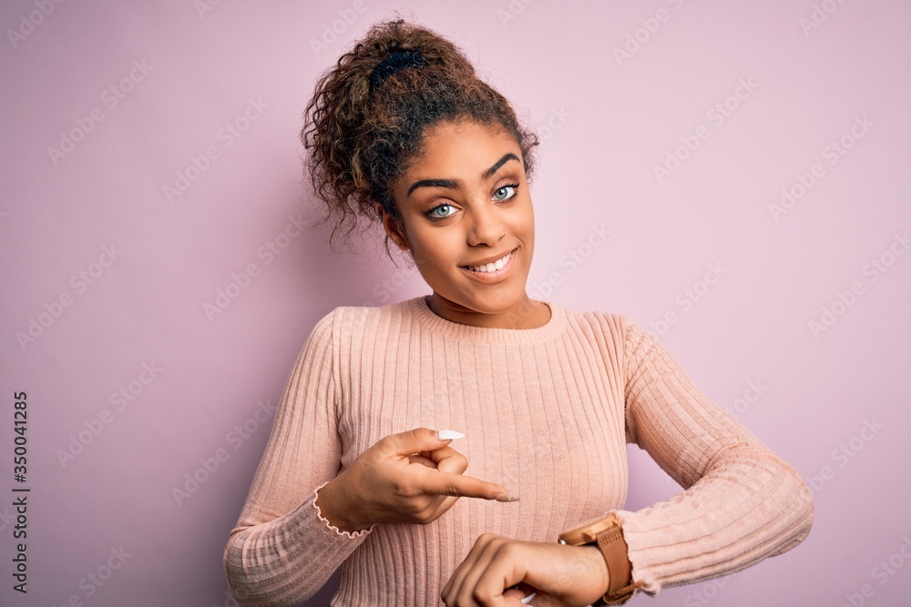 Canvas Prints Young beautiful african american girl wearing casual sweater standing over pink background In hurry pointing to watch time, impatience, upset and angry for deadline delay