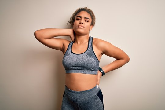 Young african american sportswoman doing sport wearing sportswear over white background Suffering of neck ache injury, touching neck with hand, muscular pain
