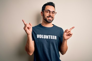 Handsome man with beard wearing t-shirt with volunteer message over white background smiling...