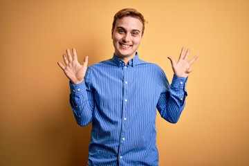 Young handsome redhead man wearing casual striped shirt over isolated yellow background showing and...