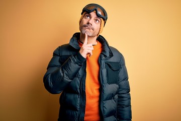 Young handsome skier man skiing wearing snow sportswear using ski goggles Thinking concentrated about doubt with finger on chin and looking up wondering