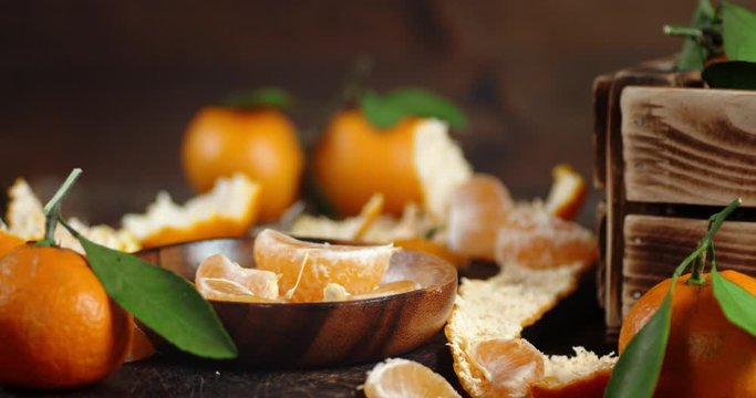 Slices of fresh tangerine fall on a plate.