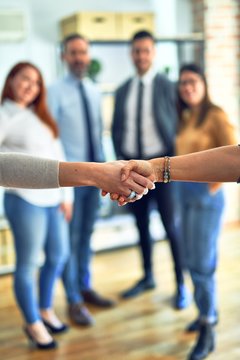 Group of business workers standing together shaking hands at the office