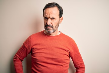 Middle age hoary man wearing casual orange sweater standing over isolated white background skeptic and nervous, frowning upset because of problem. Negative person.