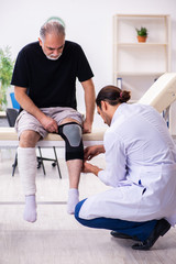 Obraz premium Old injured man visiting young male doctor traumatologist
