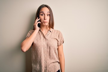 Young beautiful woman having conversation talking on the smartphone over white background depressed and worry for distress, crying angry and afraid. Sad expression.