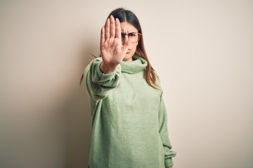 Young beautiful woman wearing casual sweater standing over isolated white background doing stop...